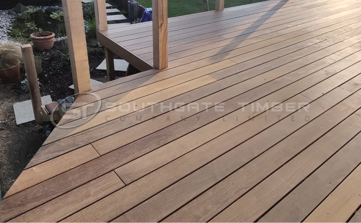 Weathered Ipe decking with a soft silver-grey patina, shown in a raised garden installation. The boards display natural ageing from sun and rain exposure, highlighting the low-maintenance, untreated finish.
