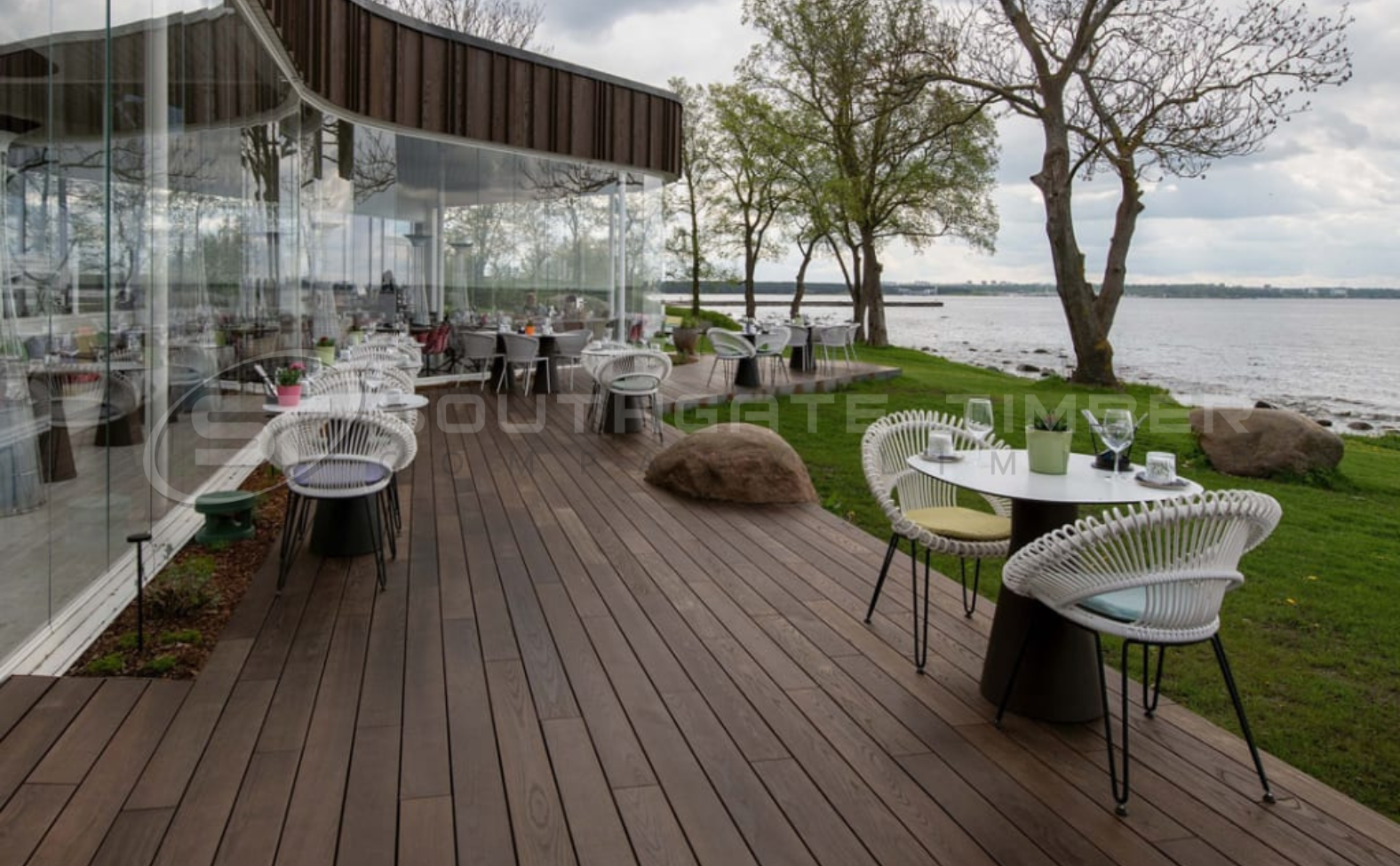 Outdoor restaurant terrace with Thermo Ash decking, showcasing its natural colour, smooth finish, and durability in a real-world commercial setting beside water.