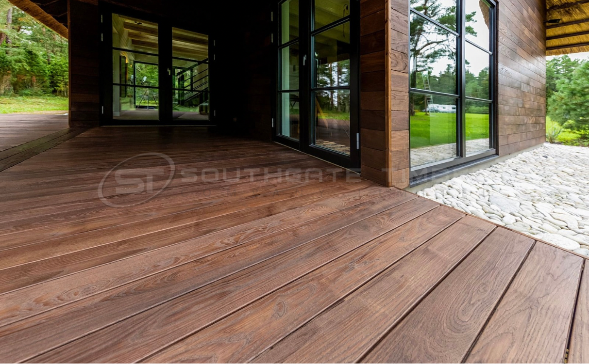 Close-up view of Thermo-Ash decking installed on a modern timber-clad home, showing the rich brown tones, smooth grain, and precise joint alignment that highlight the quality and stability of thermally modified wood decking supplied by Southgate Timber.
