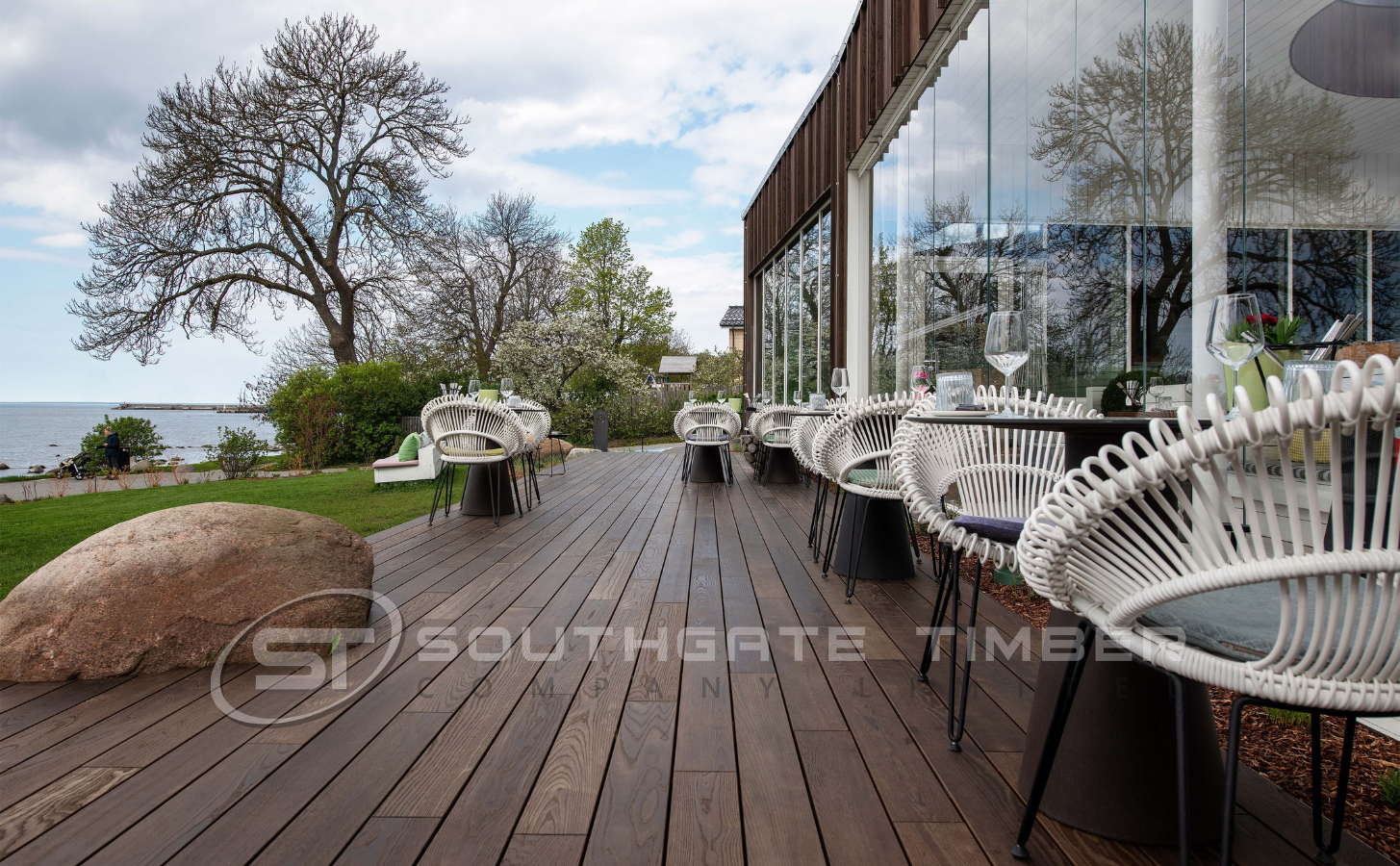 Thermory 20 x 132mm Thermo-Ash D4 SG2 decking with hidden fix system, pre-oiled finish, installed on a modern outdoor terrace beside a glass-fronted restaurant, supplied by Southgate Timber.