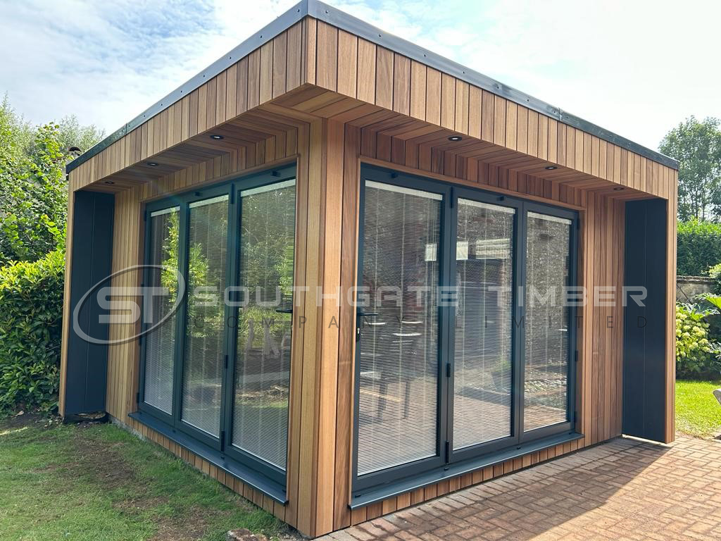 Garden room clad in Thermo Ayous 20 x 144mm Channel Groove Vertical ST6.TA, showing smooth, golden-toned boards installed vertically with a clean, contemporary profile. The cladding highlights the uniform grain, sharp shadow lines, and premium finish of Thermo Ayous, framed by modern anthracite windows and a minimalist roofline.