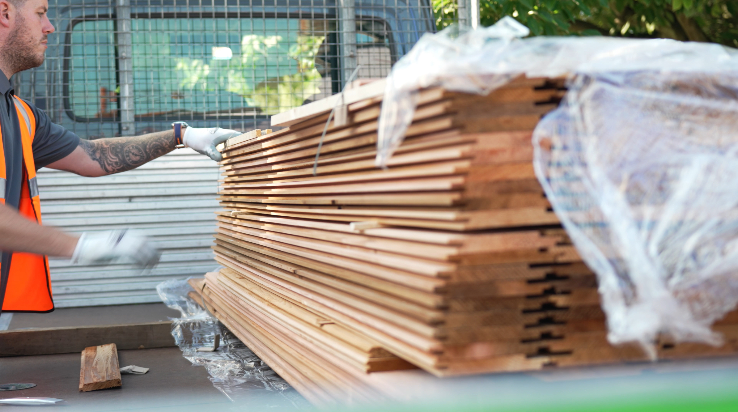 Southgate Timber staff member handling stacked timber cladding boards during order preparation for delivery, showcasing quality wood products and efficient service.