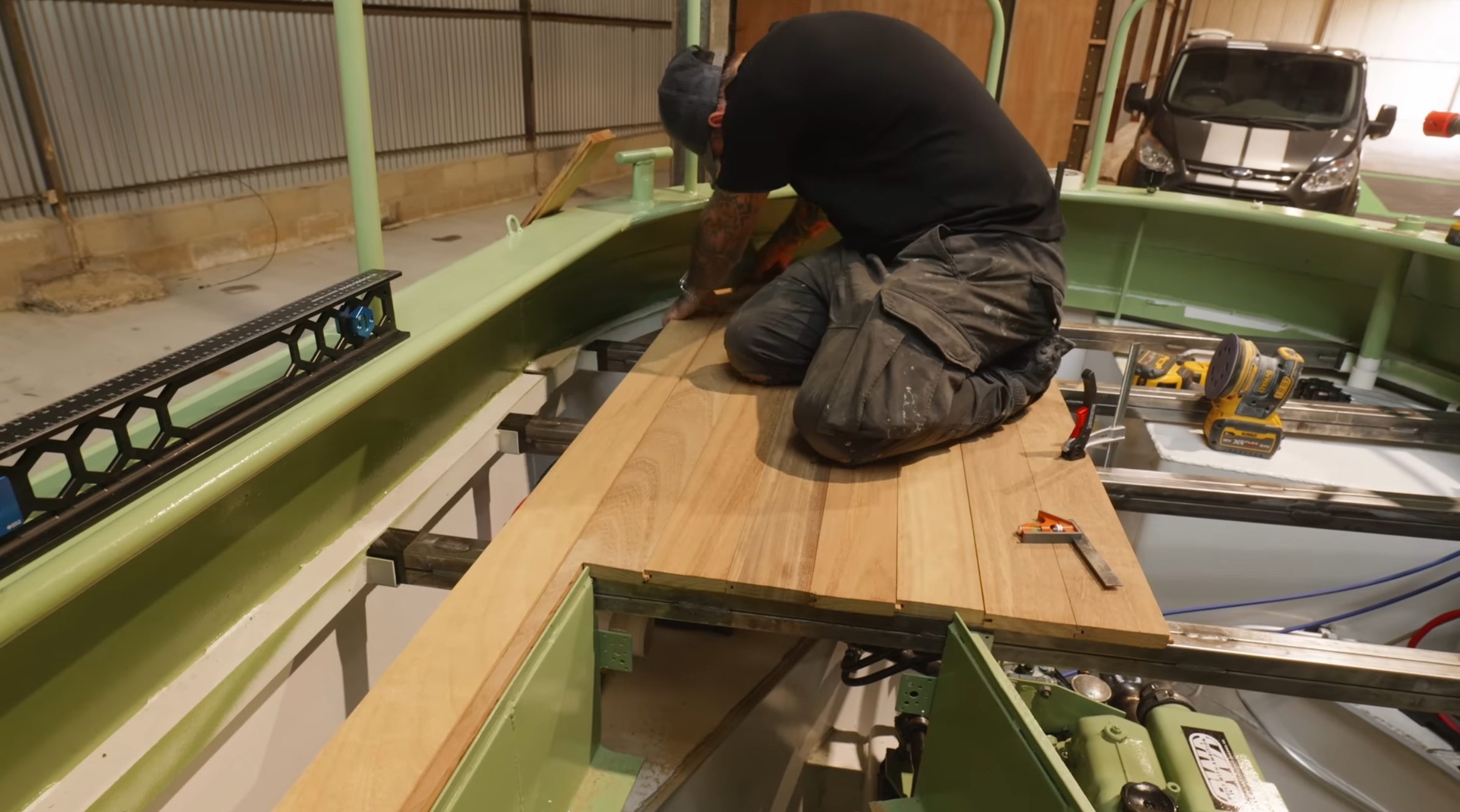 Installer fitting bespoke machined Iroko tongue and groove decking boards onto the narrowboat frame during the raffle build project supported by Southgate Timber and The Home Improvements Channel.