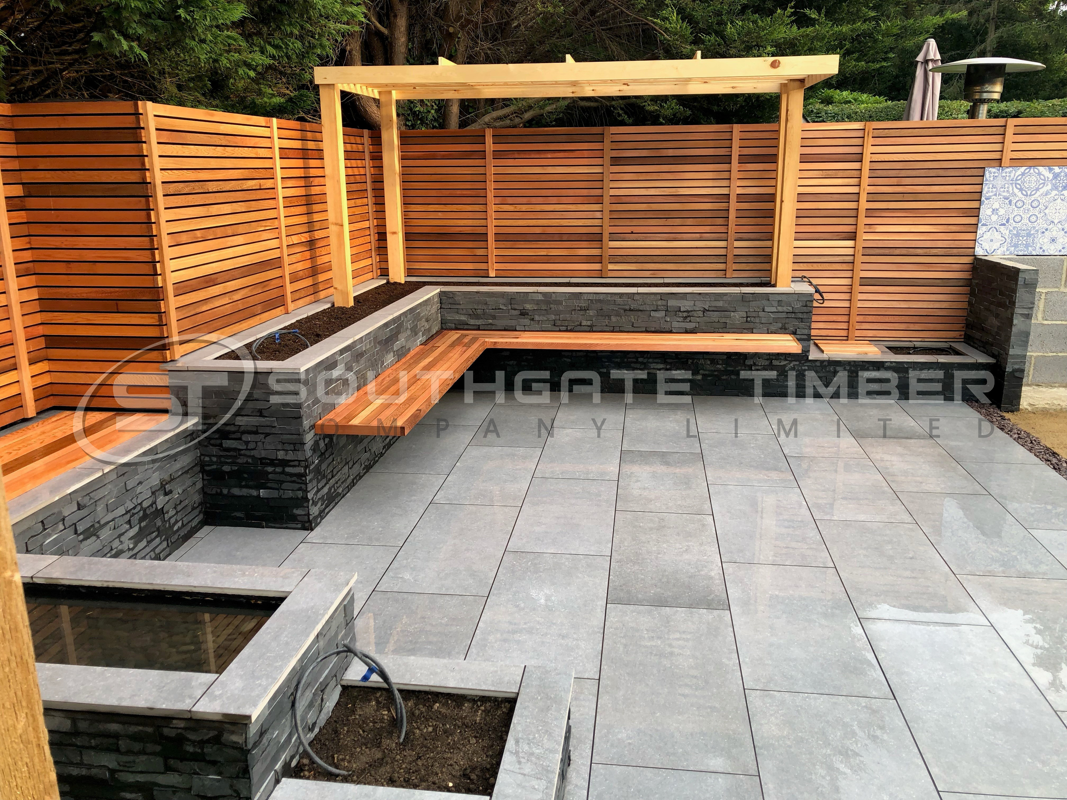 Modern garden design featuring Western Red Cedar horizontal slatted fencing supplied by Southgate Timber, paired with grey stone seating and patio paving for a contemporary outdoor living space.