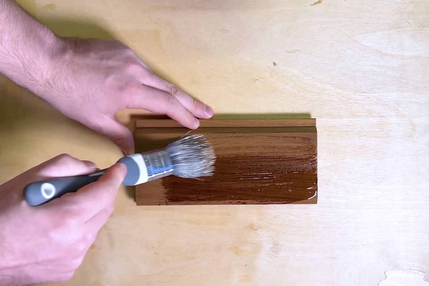 Hand applying Osmo 420 UV Protection Oil to a sample of Southgate Timber Thermo Ayous 20 × 95 mm TGV cladding, showing the rich darkened tone and enhanced grain contrast after treatment for long-term weather protection.