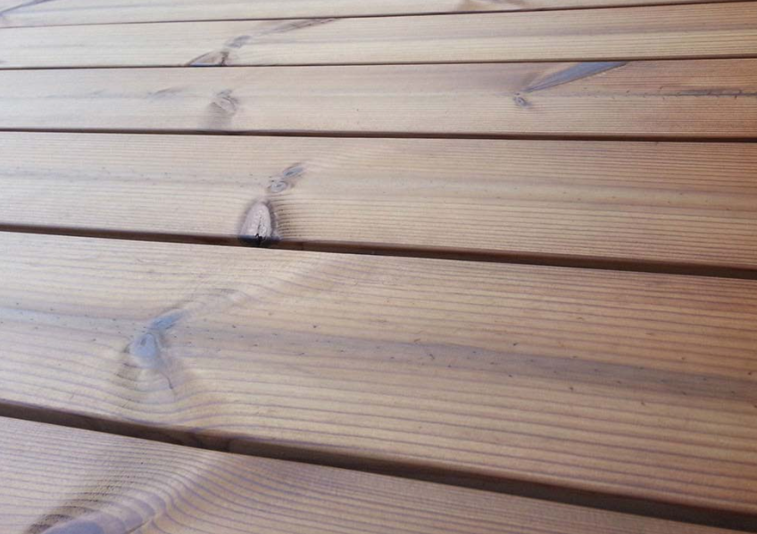 Close-up of Thermowood Pine decking boards showing the smooth, knot-detailed grain and warm golden-brown tone that highlight the natural beauty and stability of thermally modified pine decking available from Southgate Timber.