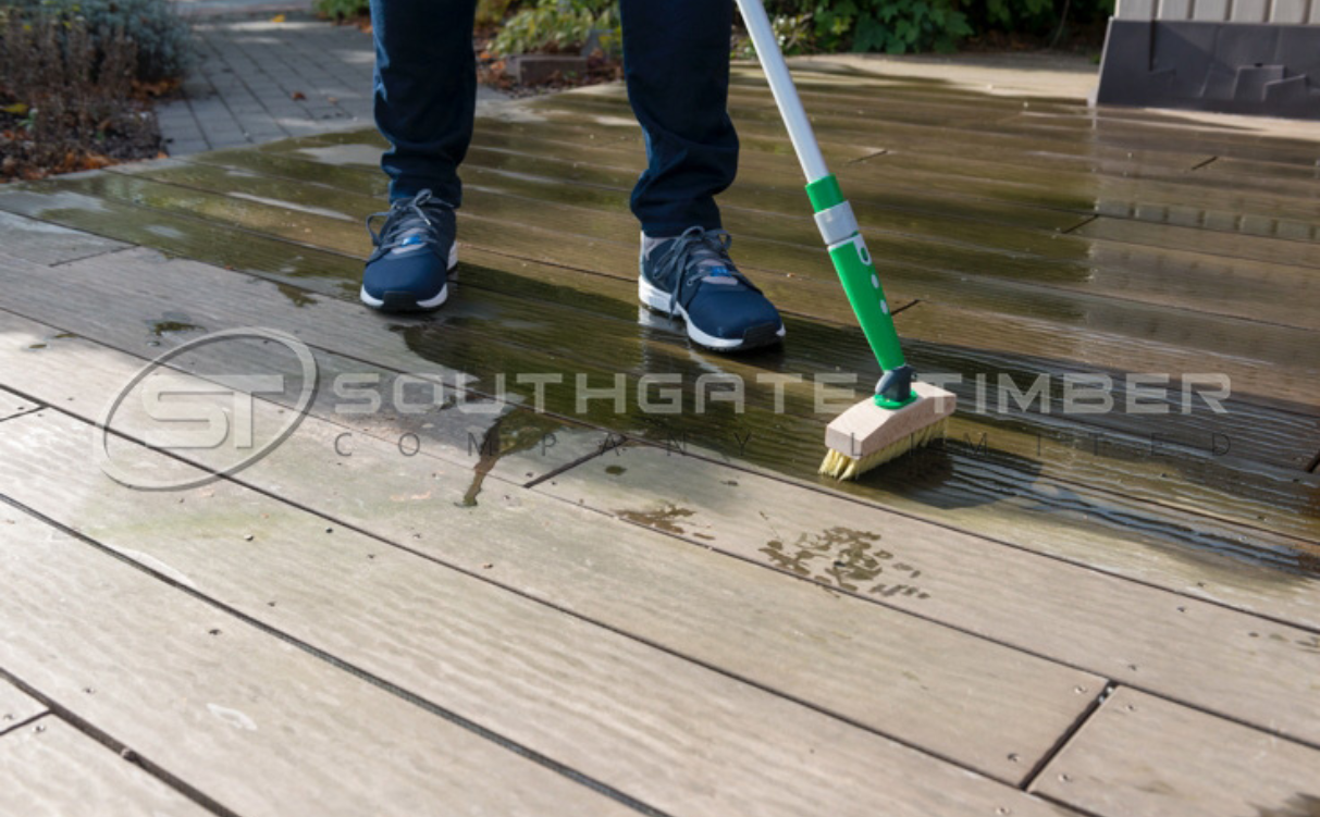 Cleaning timber decking with brush and water to remove dirt and algae buildup