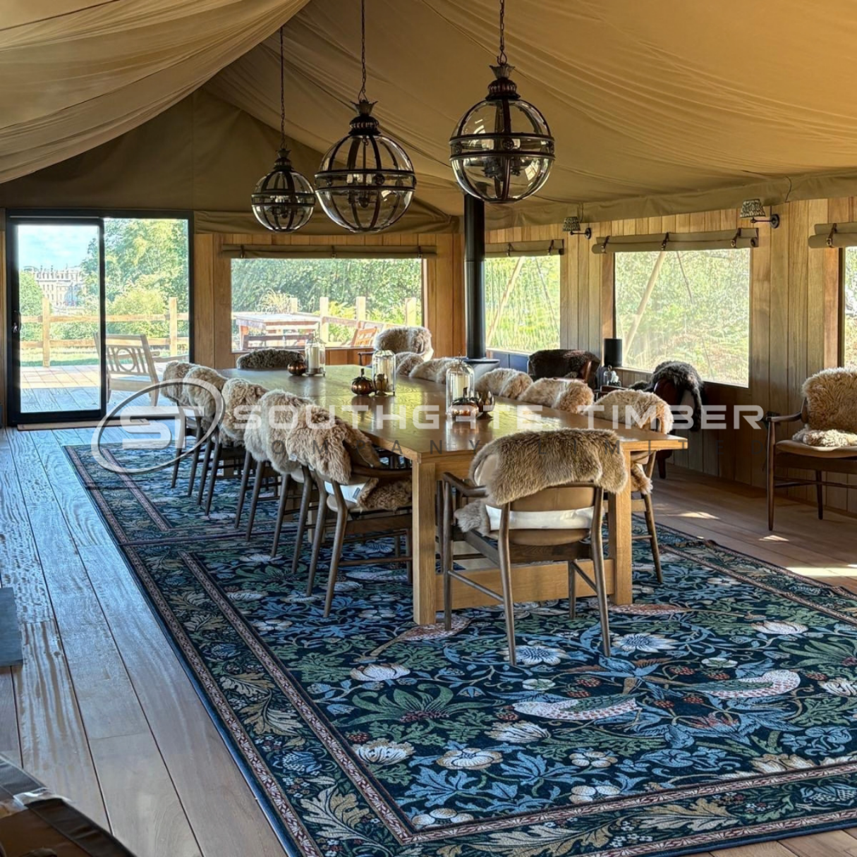 Bespoke Iroko decking used as flooring inside a luxury wedding tent, with long dining table and globe lights