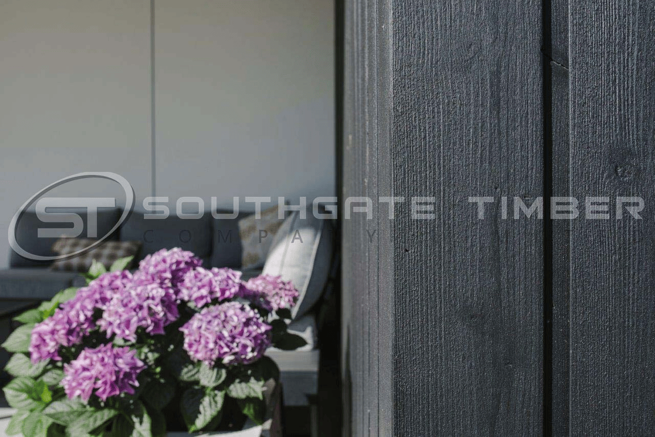 Close-up of black timber cladding boards showing the vertical grain texture and channel groove joint