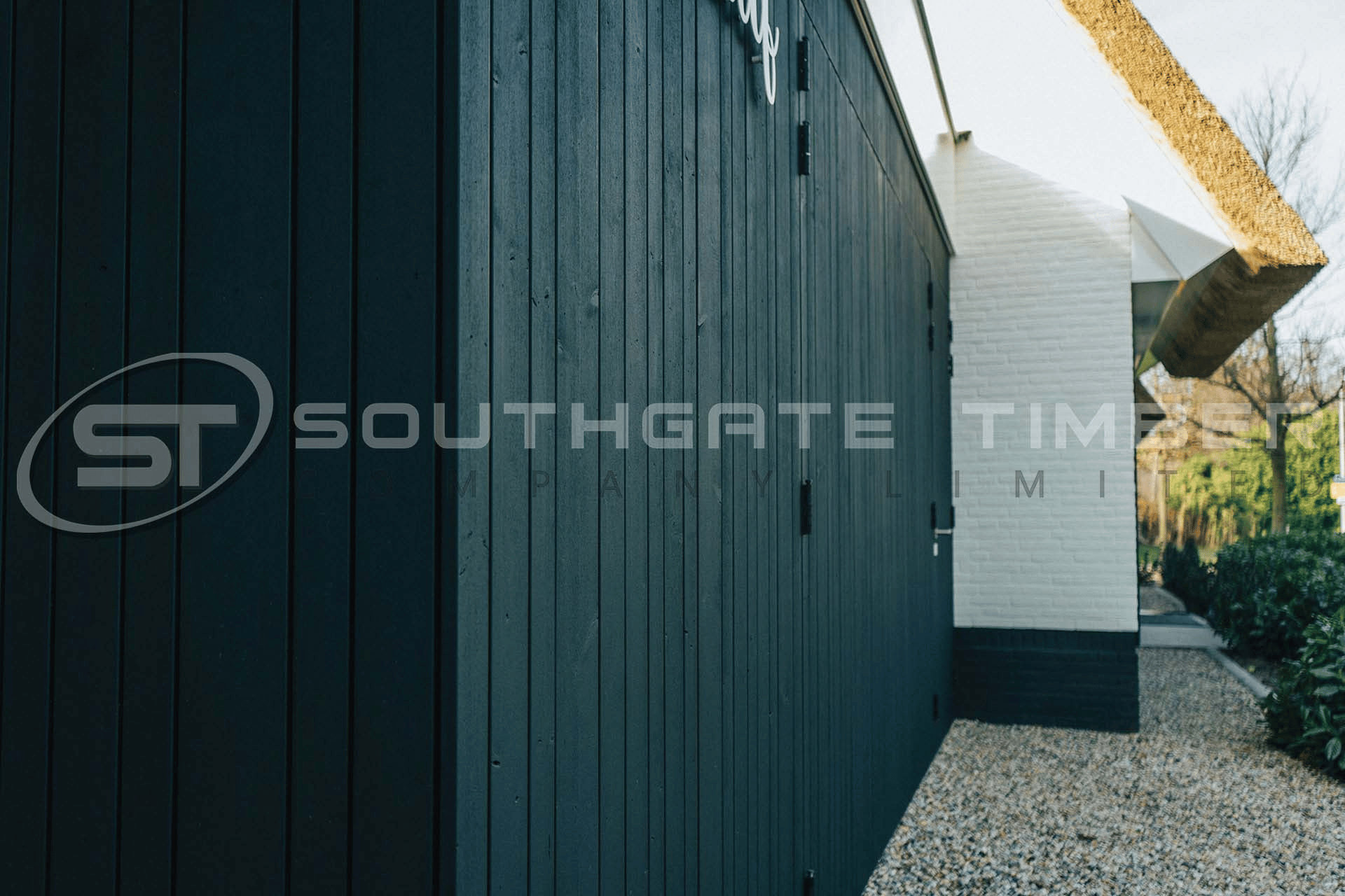 Black timber cladding on a garden room exterior, vertical channel groove profile with hinged door