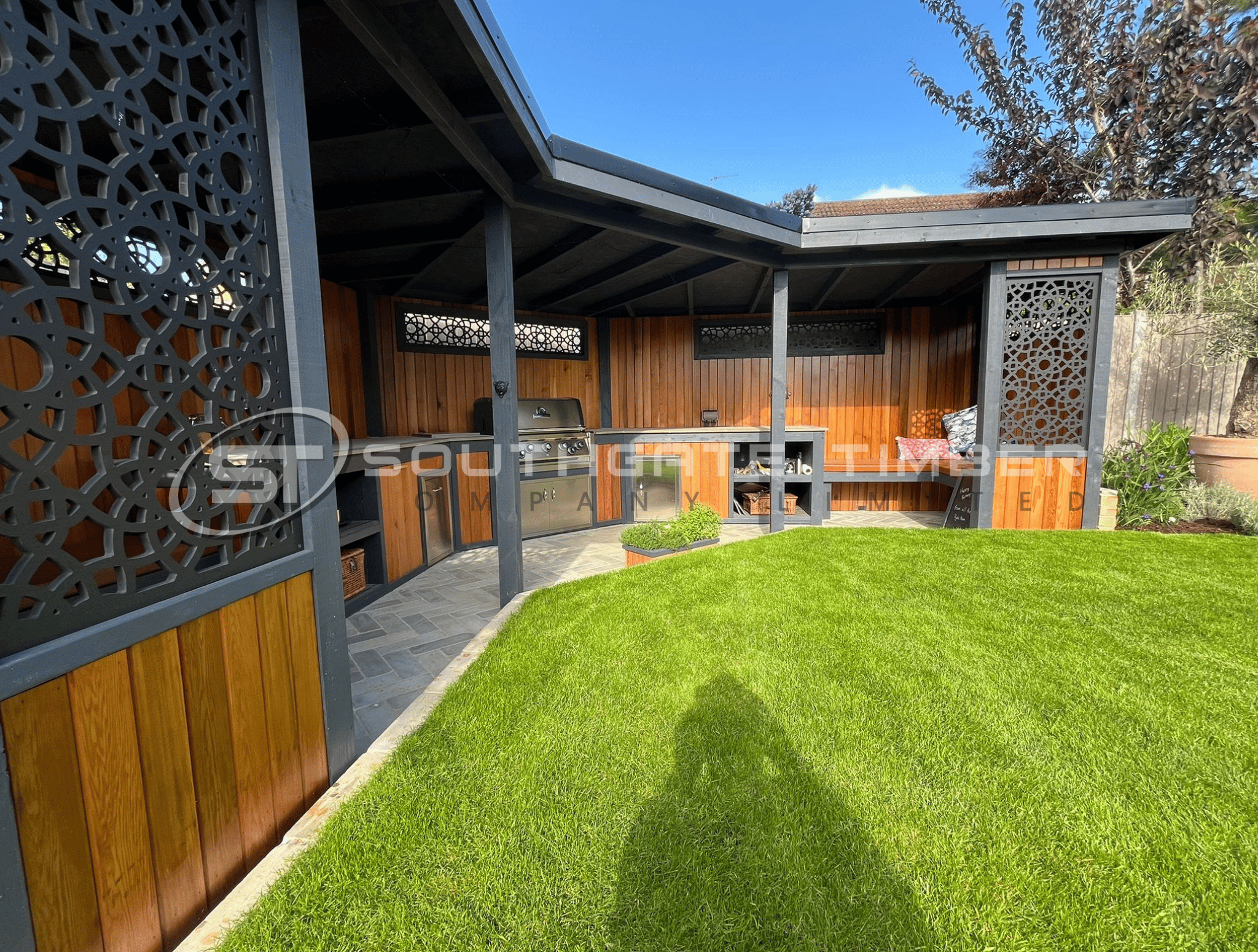 Cedar cladding outdoor kitchen and seating area under a covered garden structure