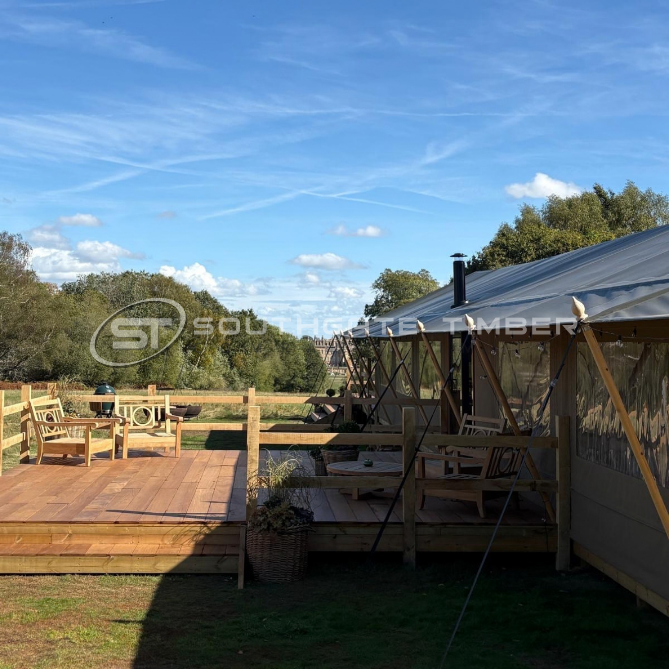Timber terrace with outdoor chairs beside the wedding tent, with Blenheim Palace in the distance