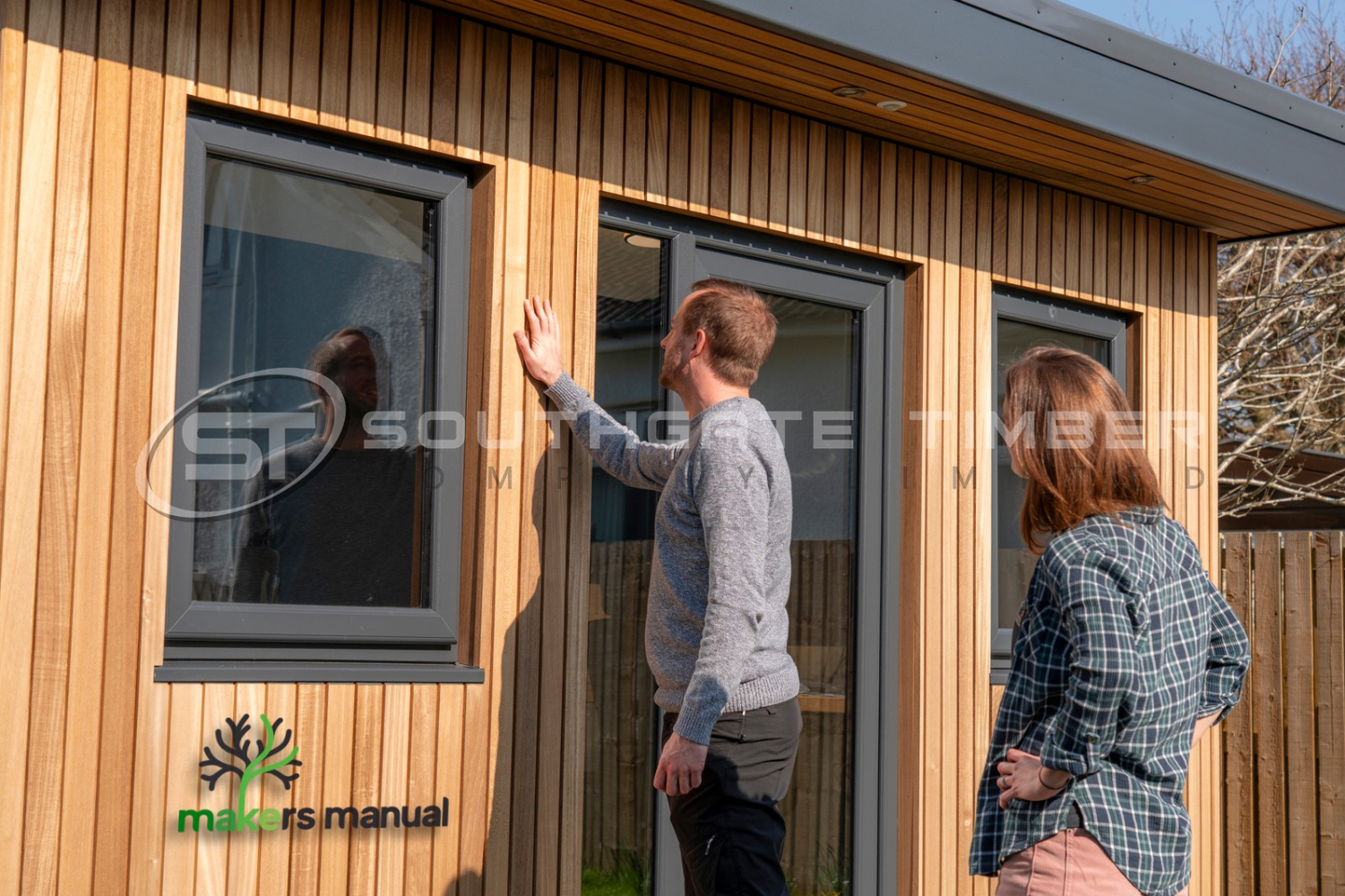Homeowners inspecting Thermo Ayous cladding on finished garden room exterior showing vertical channel groove profile and clean modern design
