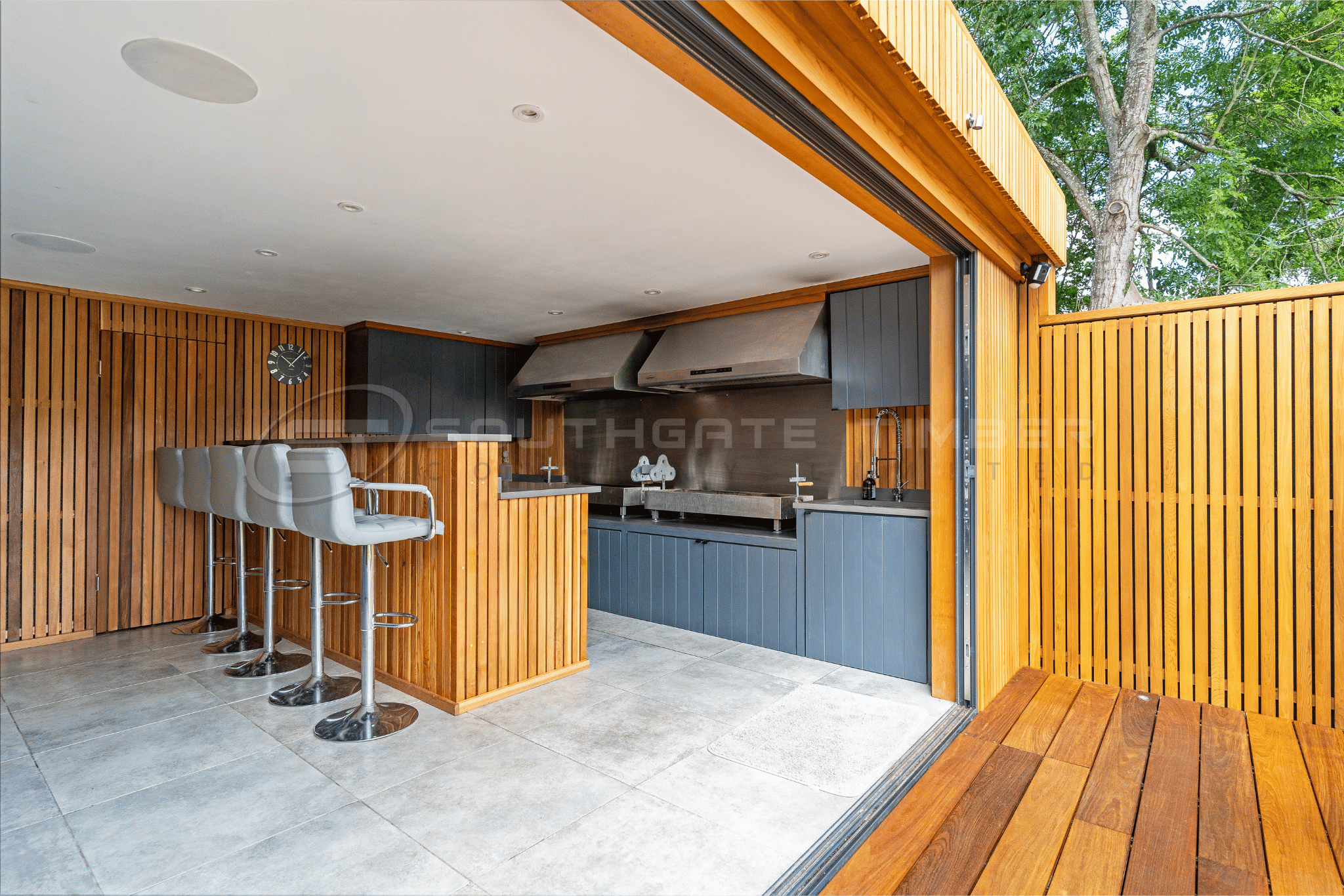 Modern outdoor kitchen featuring timber screening, hardwood decking and contemporary garden entertaining space